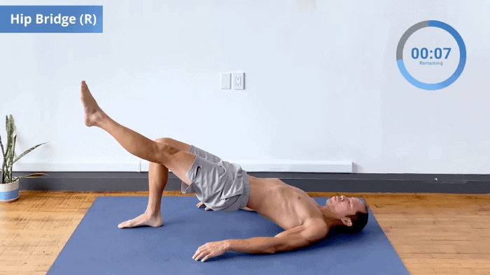 One-leg hip bridge with right foot grounded and hips elevated, shoulders retracted.
