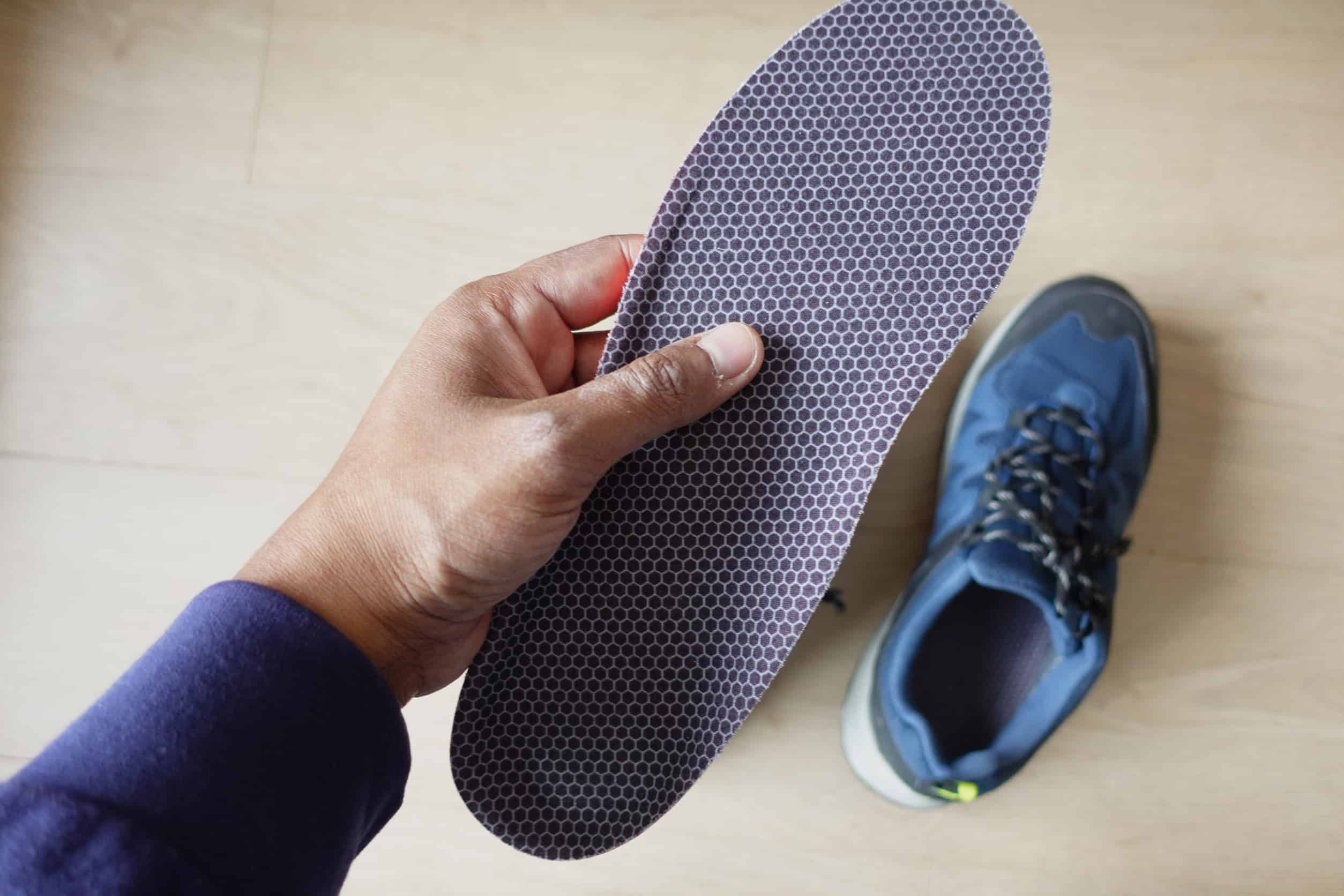 men hand putting Orthopedic insoles in shoes .